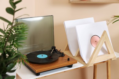 Photo of Stylish turntable with vinyl record on wooden table in room