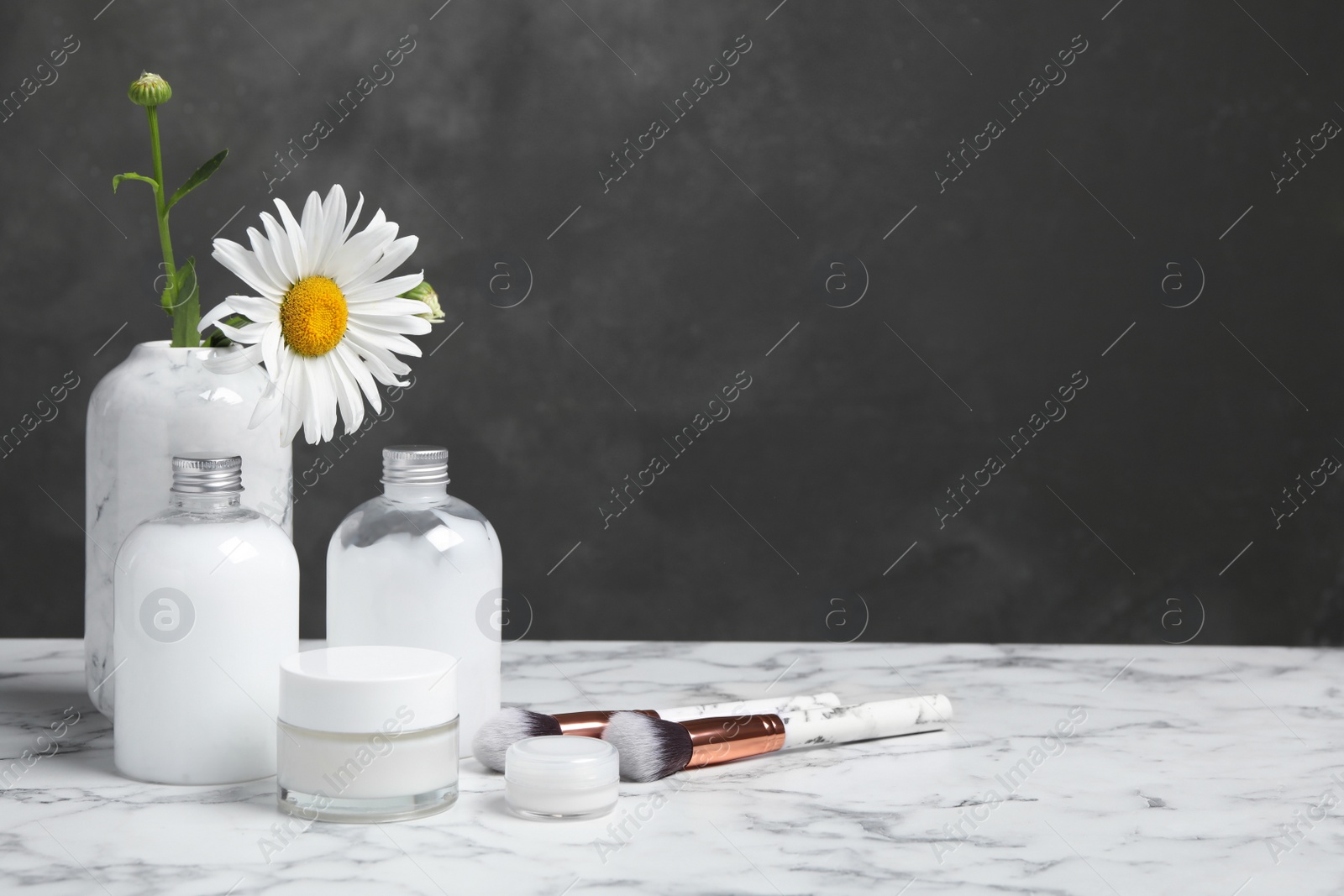 Photo of Composition with chamomile flower and cosmetic products on white marble table, space for text