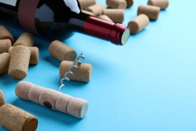 Photo of Corkscrew with wine bottle and stoppers on turquoise background