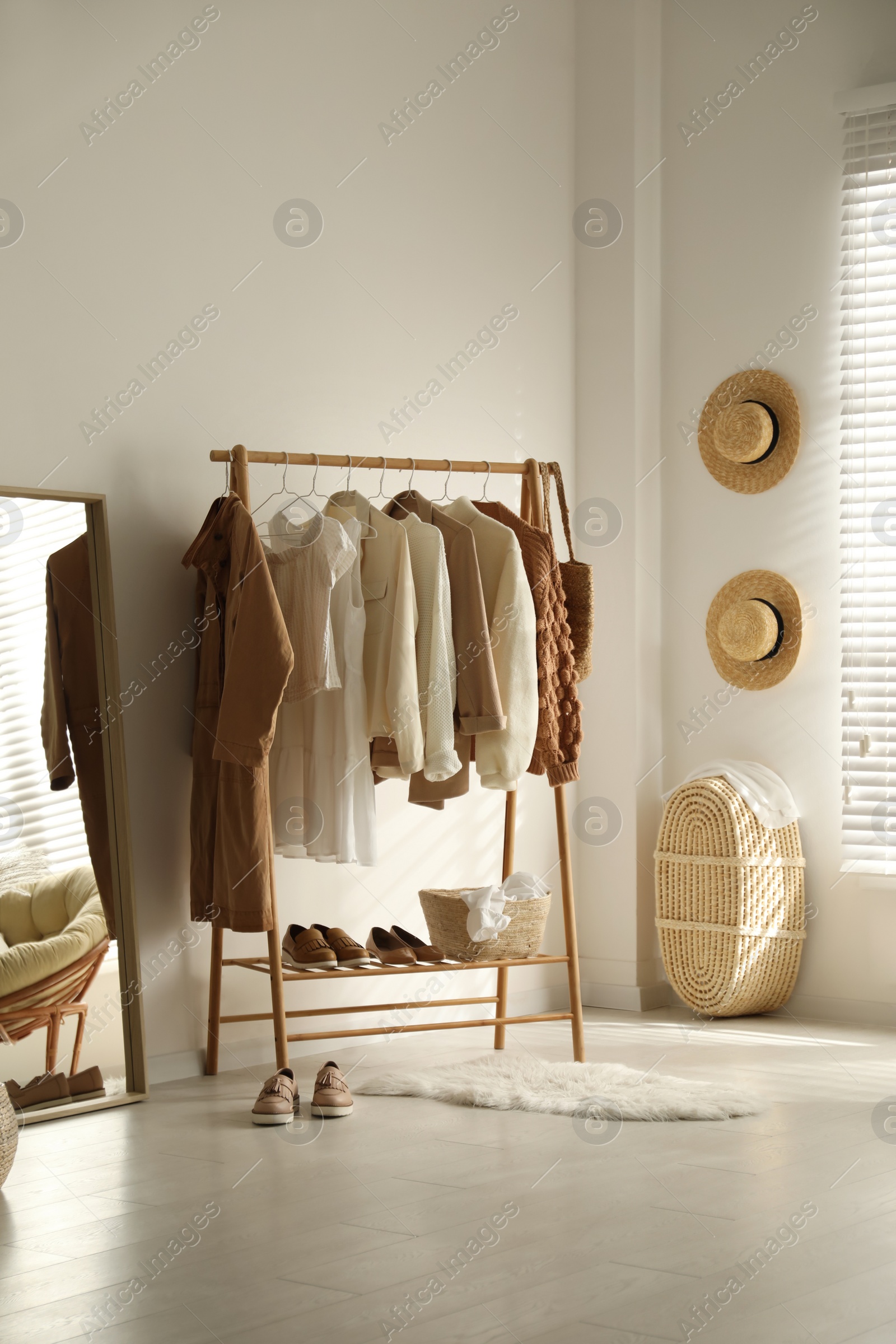 Photo of Rack with stylish women's clothes in dressing room. Modern interior design