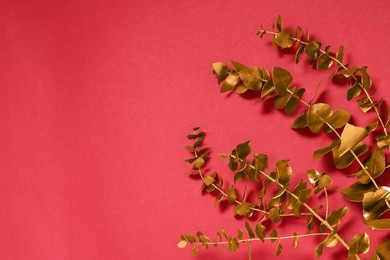 Golden decorative branches on red background, flat lay. Space for text