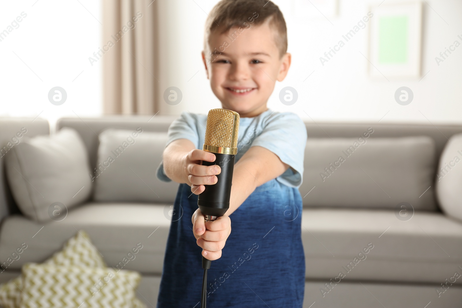 Photo of Cute funny boy with microphone in living room