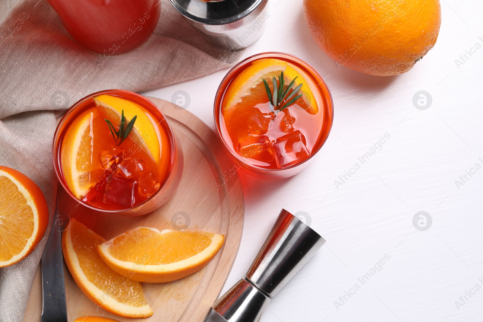 Photo of Aperol spritz cocktail, rosemary and orange slices in glasses on white wooden table, flat lay. Space for text