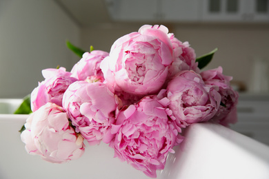 Photo of Bouquet of beautiful pink peonies in kitchen sink, closeup