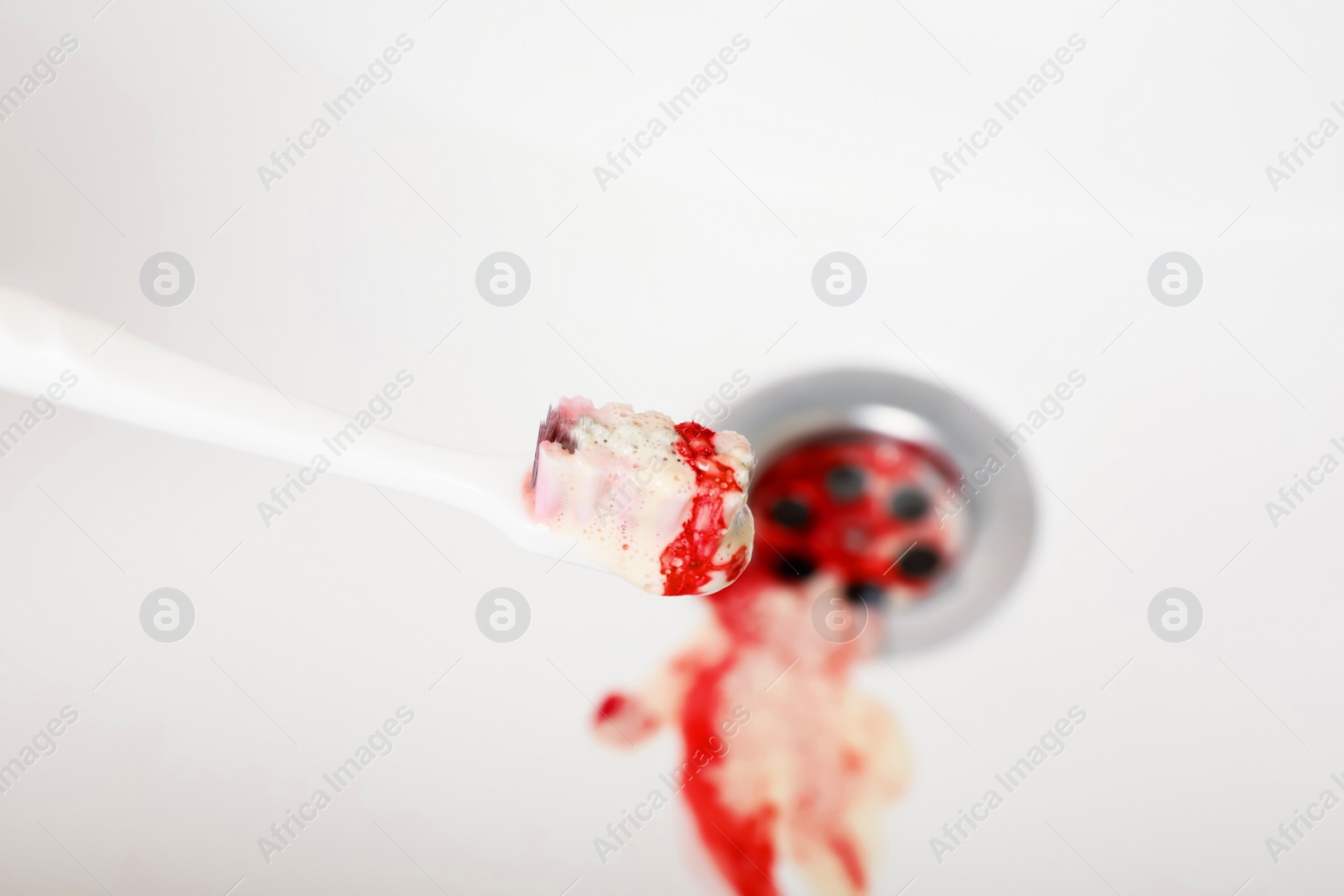 Photo of Toothbrush with paste and blood over sink, closeup. Gum inflammation