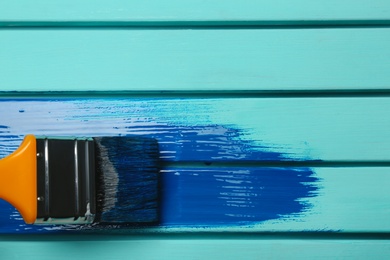 Photo of Brush and blue paint stroke on wooden background, top view. Space for text