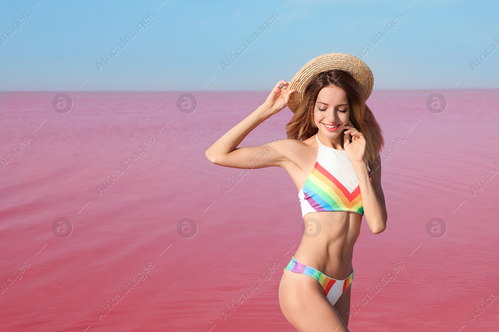 Photo of Beautiful woman in swimsuit posing near pink lake on sunny day