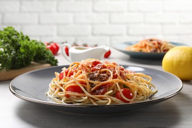 Delicious pasta with anchovies, tomatoes and parmesan cheese served on white wooden table