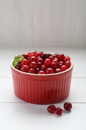 Photo of Fresh ripe cranberries in bowl on white wooden table, closeup