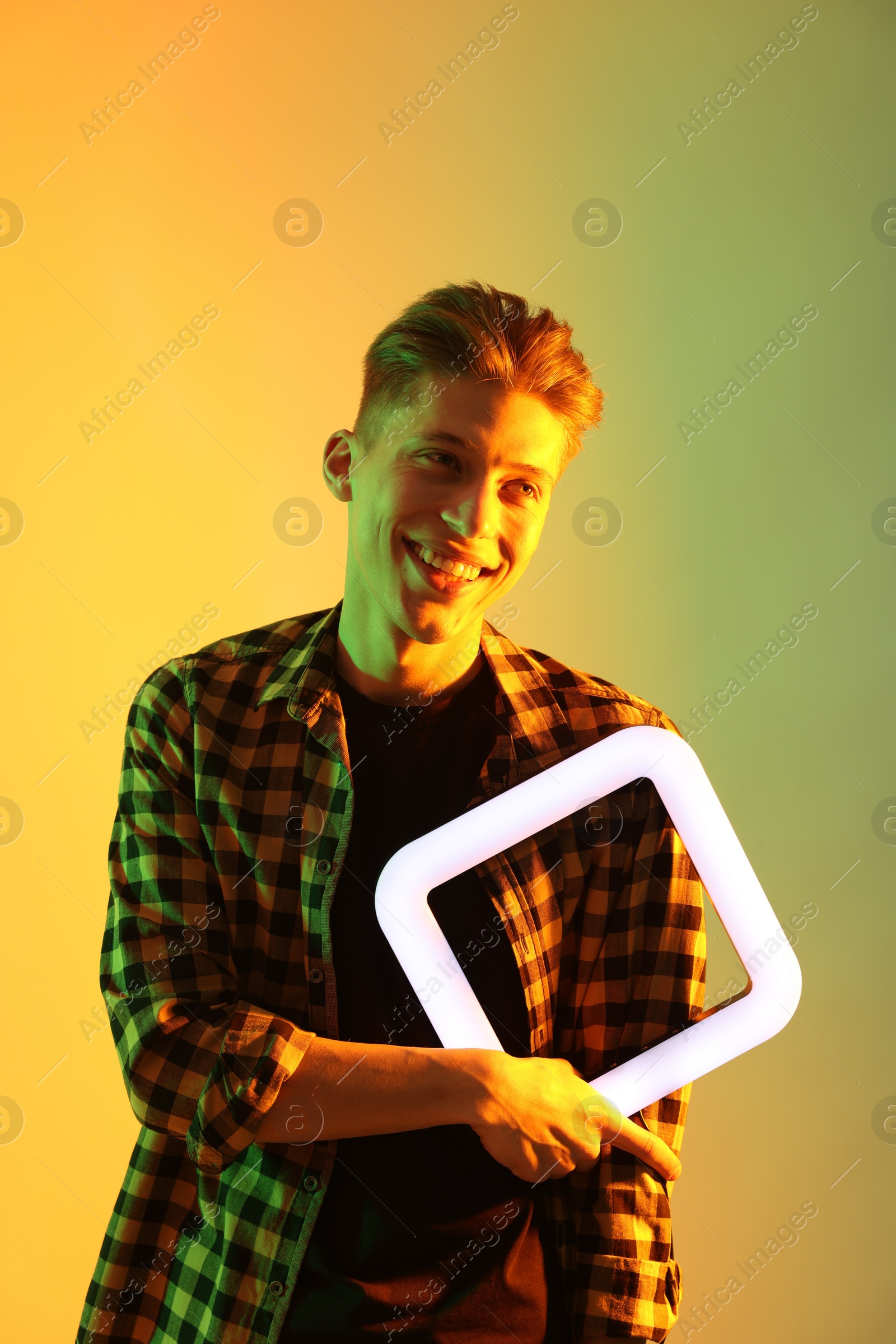 Photo of Young man with square lamp on color background in neon lights