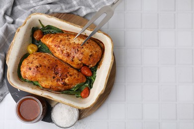 Photo of Baked chicken fillets with vegetables and marinade on white tiled table, flat lay. Space for text