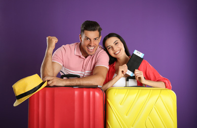 Happy couple with suitcases for summer trip on purple background. Vacation travel