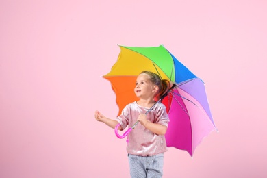 Little girl with rainbow umbrella on color background