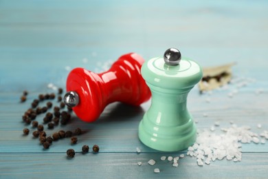 Photo of Salt and pepper shakers on turquoise wooden table, closeup. Spice mill