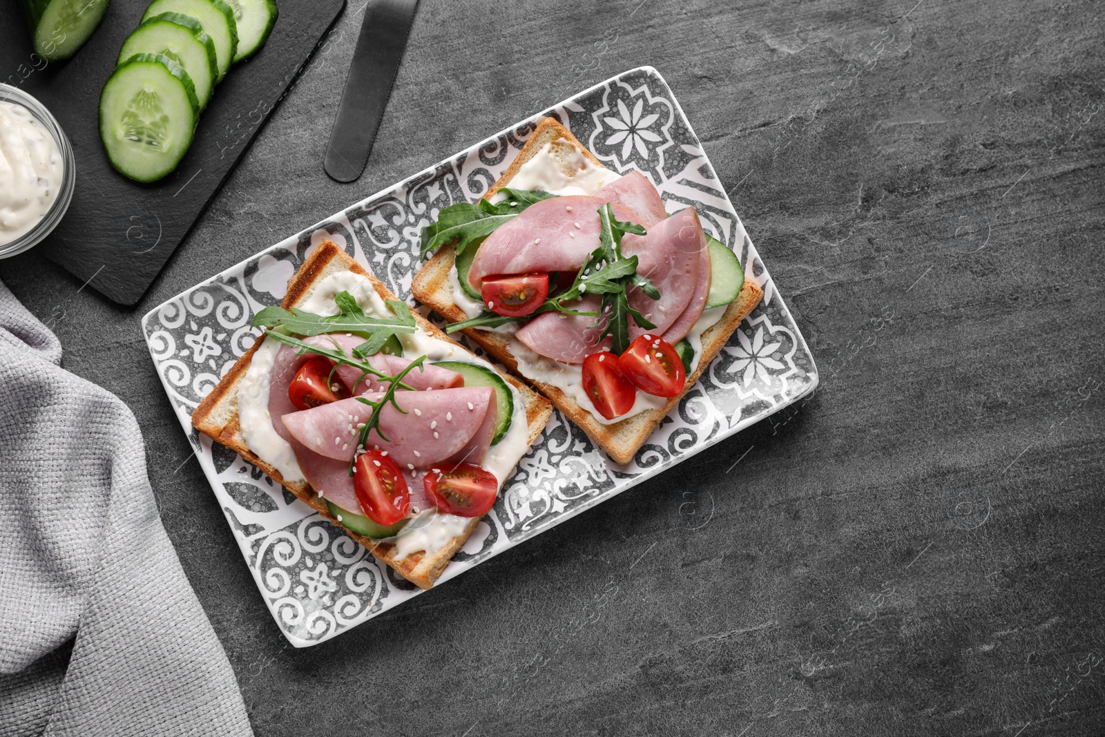 Photo of Tasty sandwiches with ham served on grey table, flat lay