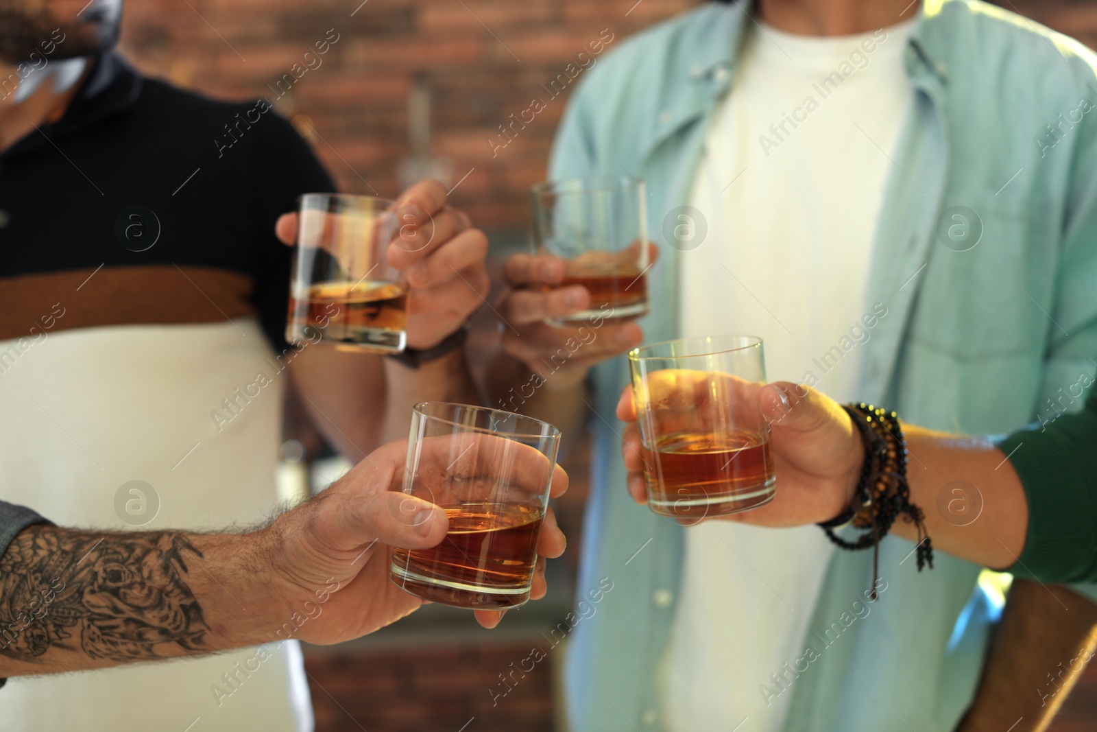 Photo of Group of friends drinking whiskey together indoors, closeup