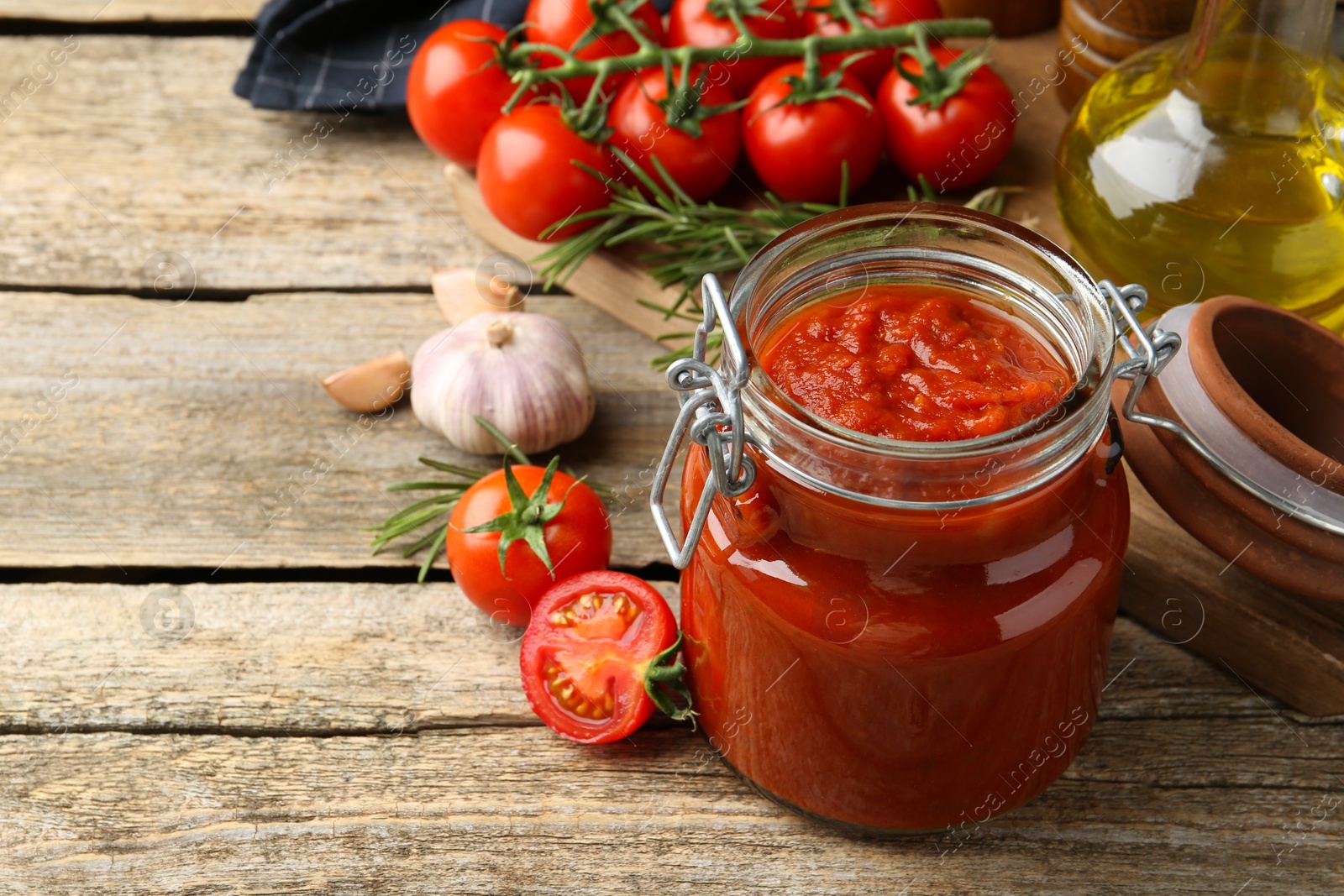 Photo of Homemade tomato sauce in jar and ingredients on wooden table. Space for text