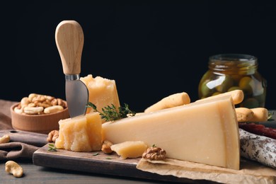 Photo of Delicious parmesan cheese with olives and walnuts on wooden table