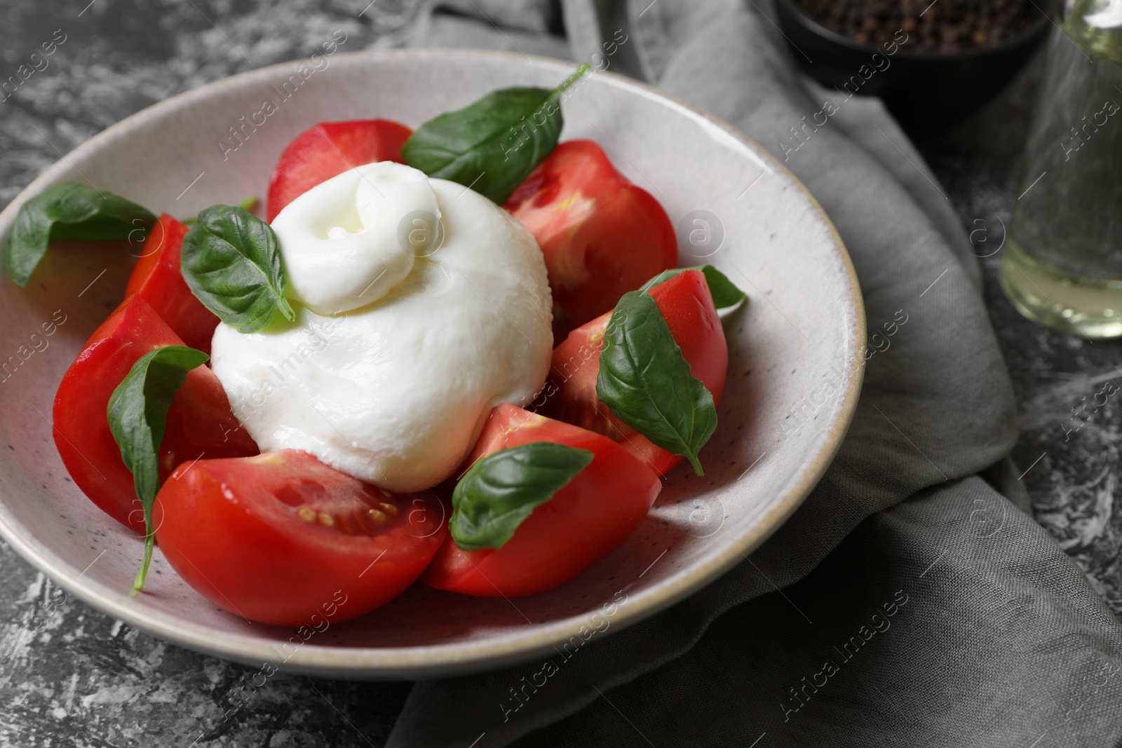 Photo of Delicious burrata cheese with tomatoes and basil on grey table, closeup. Space for text