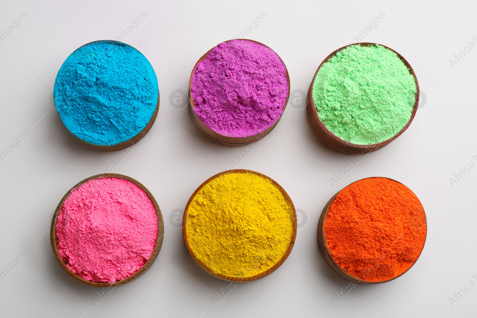 Photo of Colorful powders in bowls on light background, flat lay. Holi festival celebration