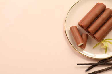 Photo of Glazed curd cheese bars, vanilla pods and flower on light pink background, top view. Space for text