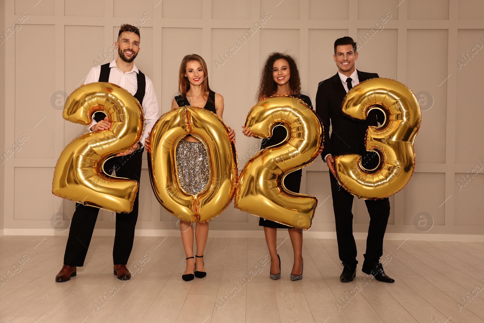 Photo of Happy friends with golden 2023 balloons indoors. New Year celebration