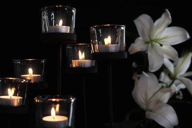 Photo of Burning candles and flowers on dark background. Funeral symbol