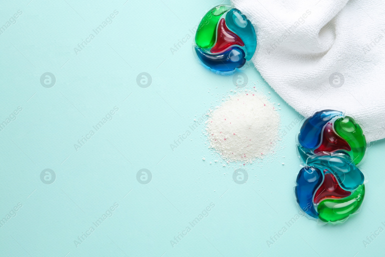 Photo of Laundry capsules, detergent powder and towel on turquoise background, flat lay. Space for text