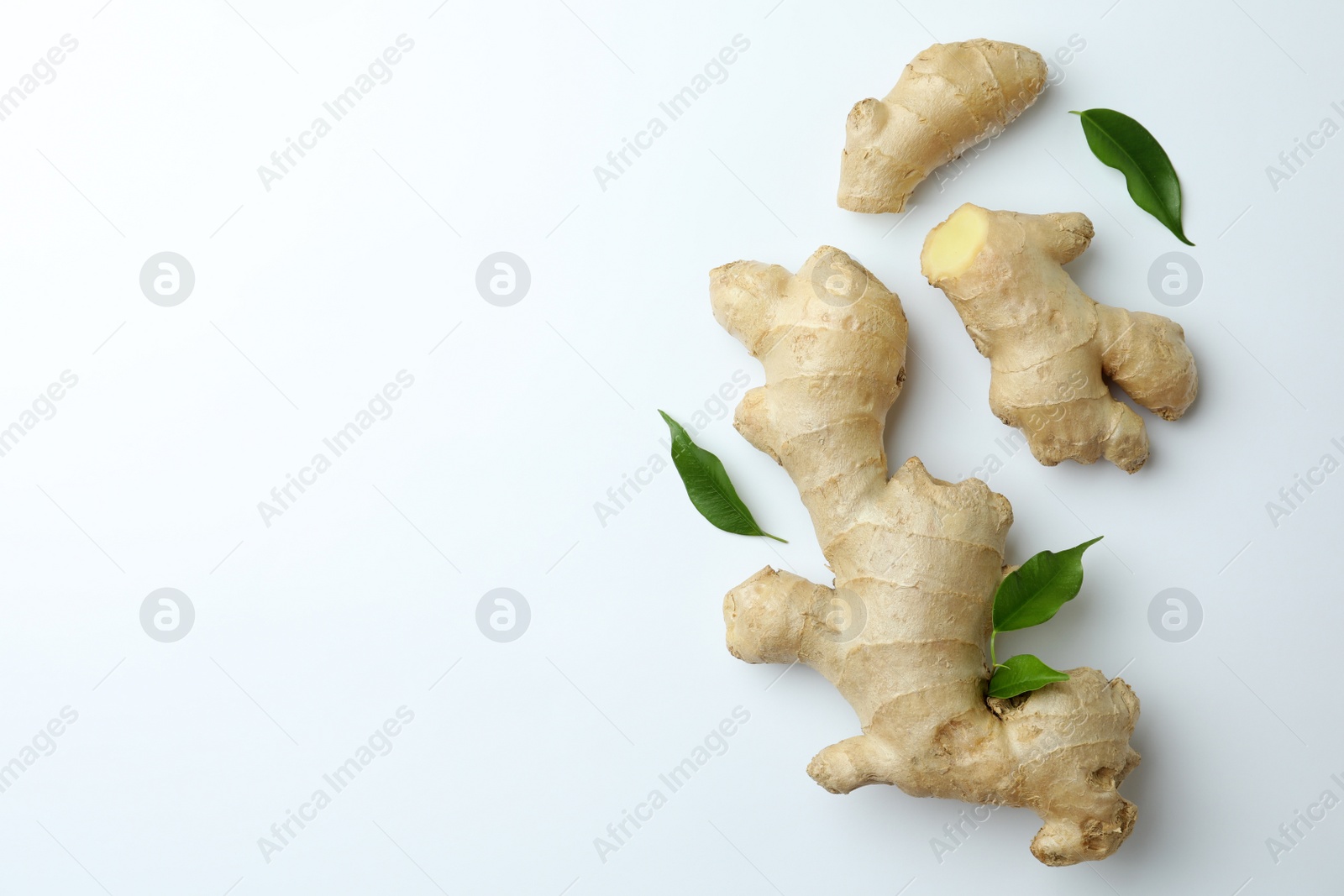 Photo of Fresh ginger with green leaves on white background, flat lay. Space for text