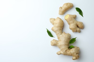 Fresh ginger with green leaves on white background, flat lay. Space for text