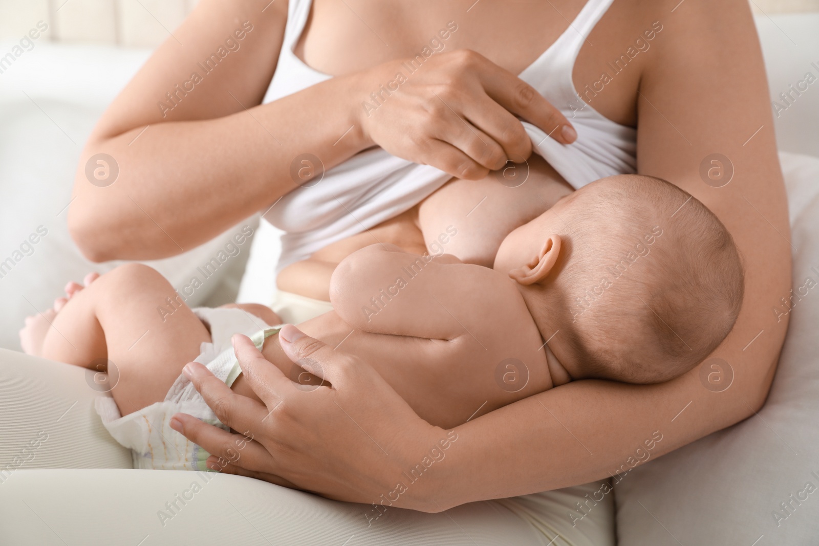 Photo of Young woman breastfeeding her little baby at home, closeup