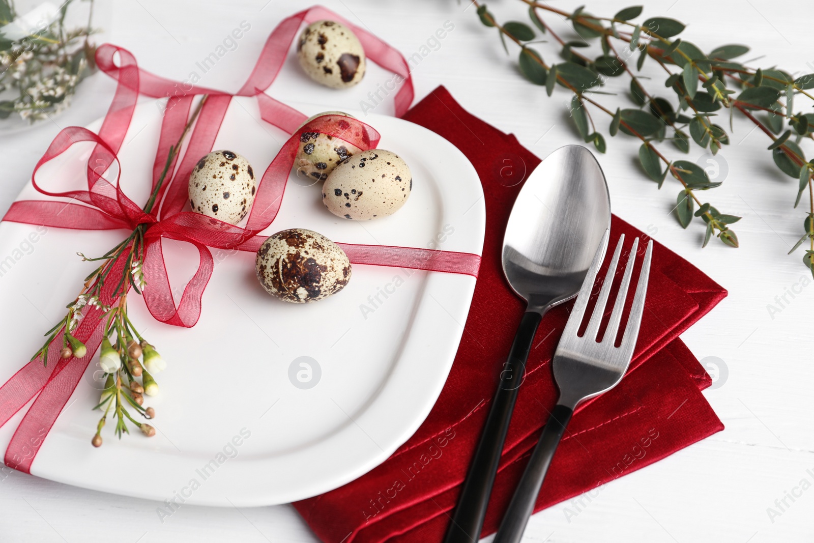 Photo of Festive Easter table setting with ribbon, floral decor and quail eggs on white background