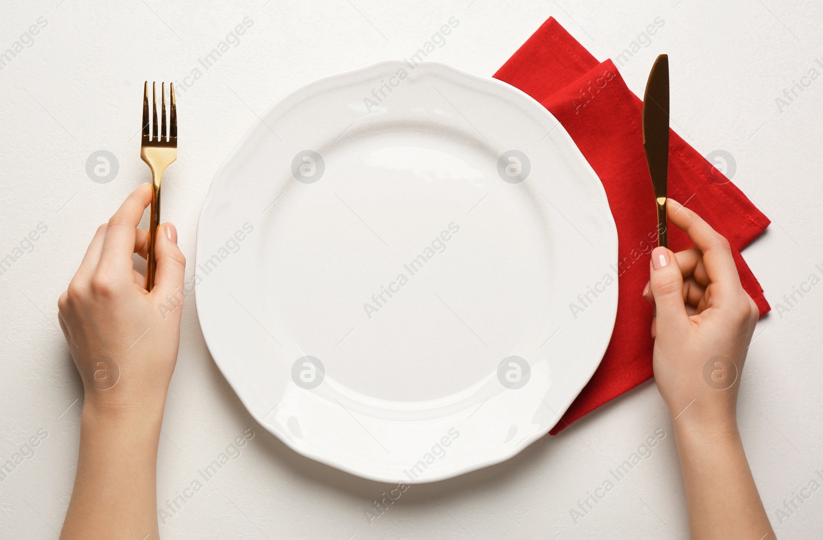 Photo of Woman with empty plate and cutlery at white table, top view