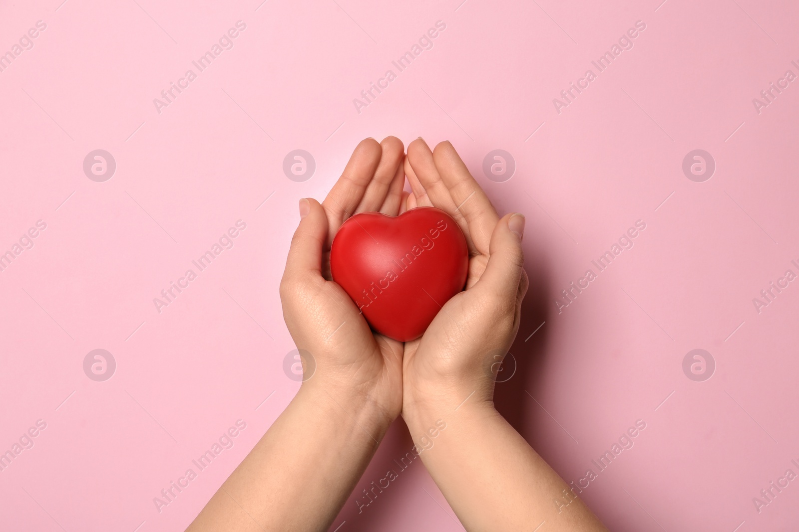 Photo of Woman holding decorative heart on pink background, top view