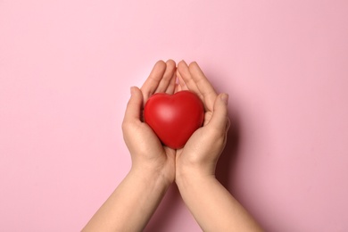 Photo of Woman holding decorative heart on pink background, top view