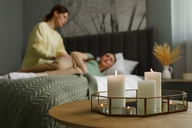 Photo of Doula working with pregnant woman in bedroom, focus on burning candles. Preparation for child birth