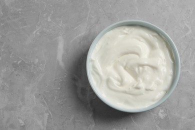 Photo of Bowl of fresh yogurt on grey table, top view. Space for text