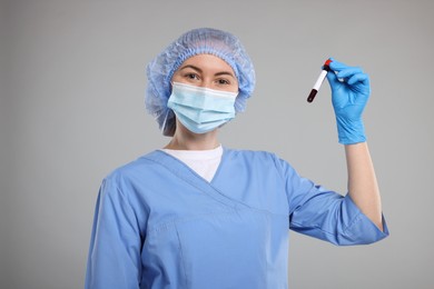 Laboratory testing. Doctor with blood sample in tube on light grey background