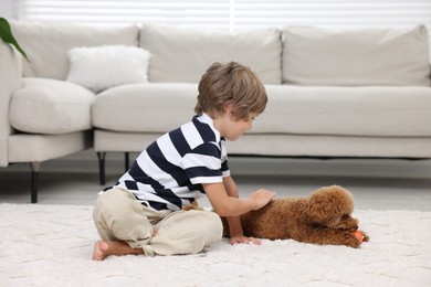 Photo of Little child and cute puppy on carpet at home. Lovely pet