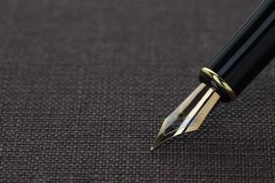 Photo of Stylish fountain pen on dark textured surface, closeup. Space for text