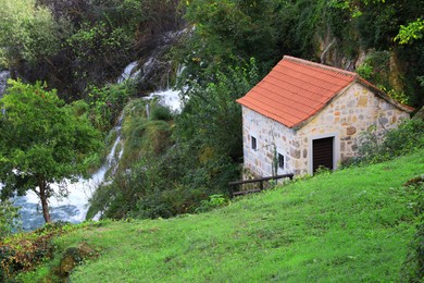 Photo of Picturesque view of beautiful waterfall and building outdoors