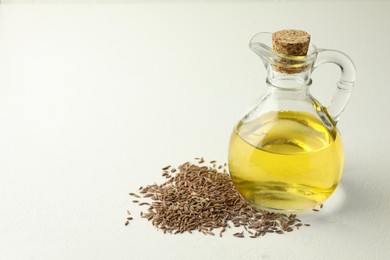 Photo of Caraway (Persian cumin) seeds and fresh oil on white table, space for text
