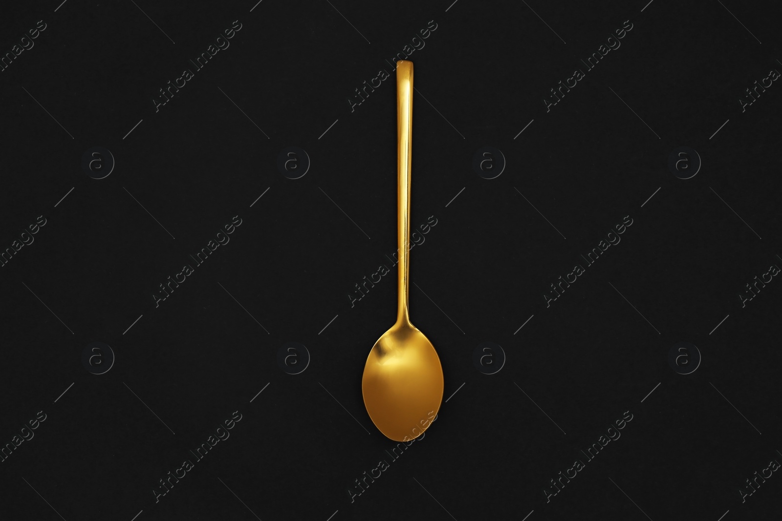 Photo of Gold spoon on black background, top view