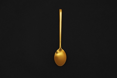 Photo of Gold spoon on black background, top view