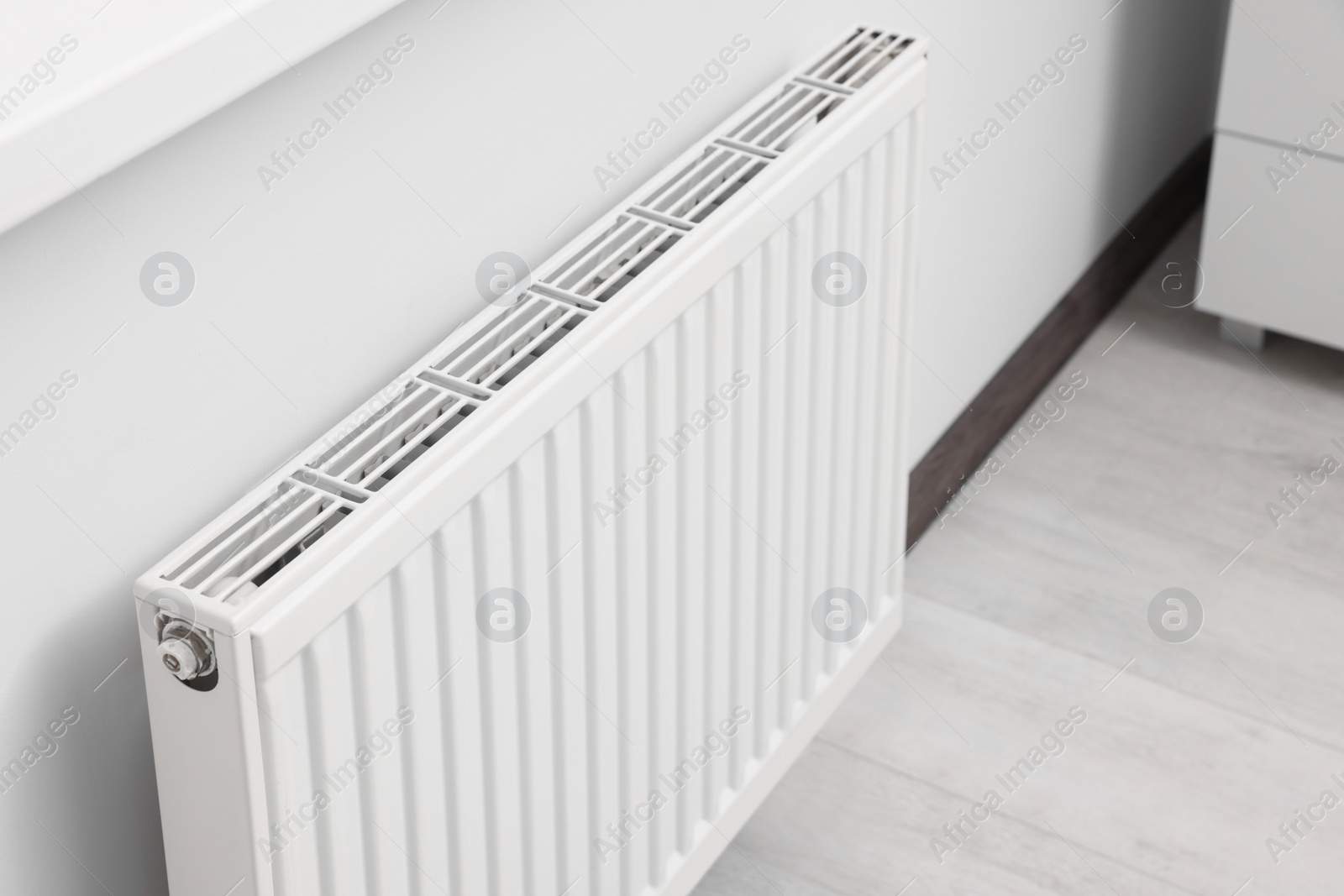 Photo of Modern radiator on white wall in room. Central heating system