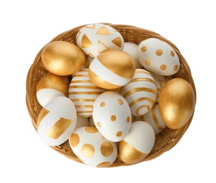 Photo of Wicker basket full of eggs decorated with gold paint on white background, top view