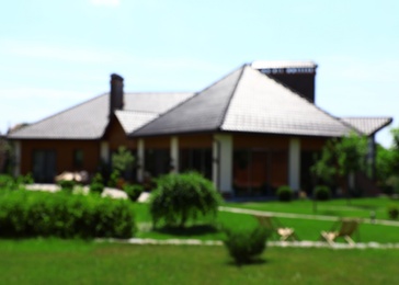 Blurred view of modern house and beautiful garden on sunny day