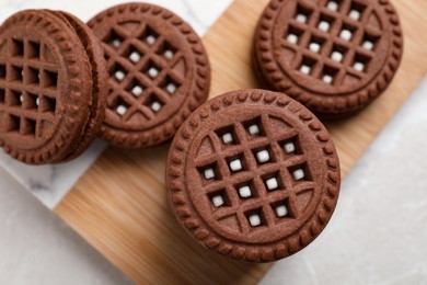 Tasty chocolate sandwich cookies with cream on light table, flat lay