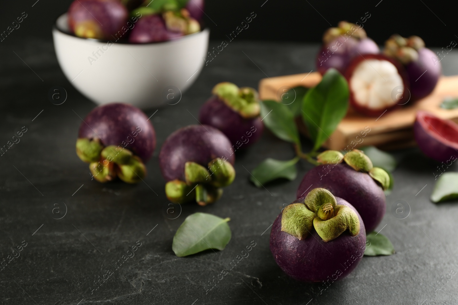 Photo of Fresh ripe mangosteen fruits on dark grey table
