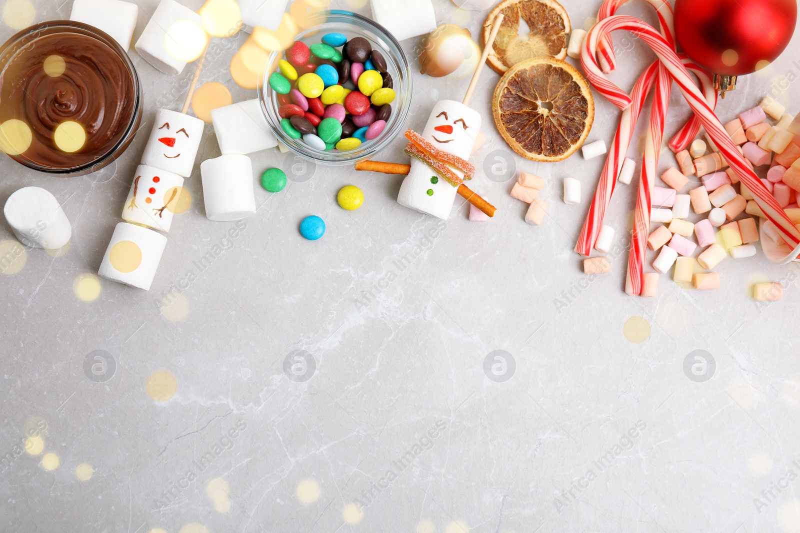 Image of Flat lay composition with funny snowmen made of marshmallows on light marble table, space for text. Bokeh effect 